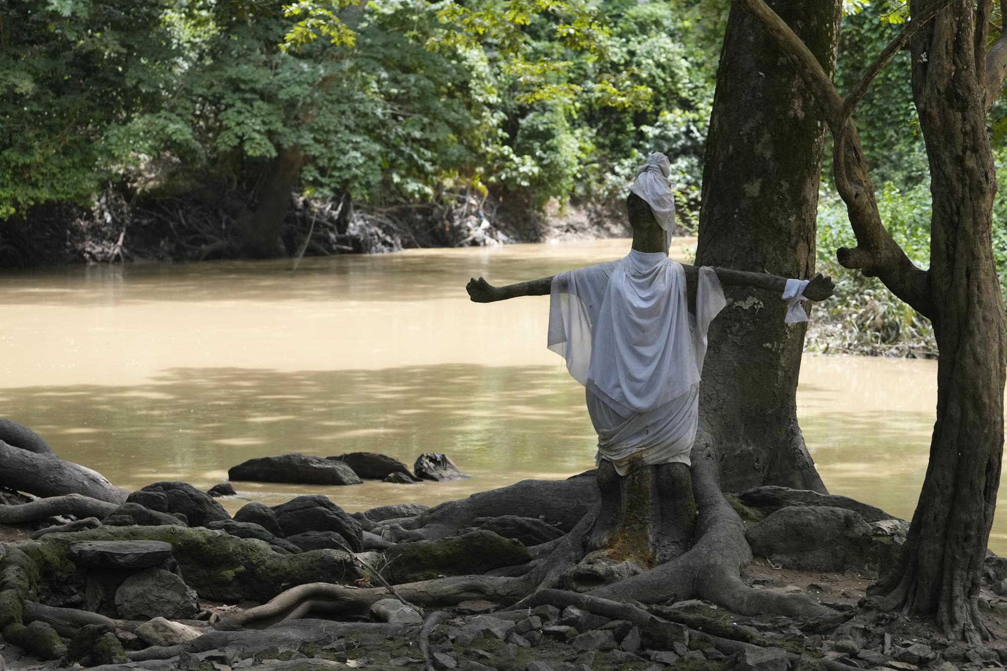 A statue of the goddess of fertility stands at the sacred Osun River in Osogbo, Nigeria, on Sunday, May 29, 2022. Some say the goddess heals them of afflictions when they drink or bathe in the river, and others say she can provide wealth or fertility. (AP Photo/Sunday Alamba)