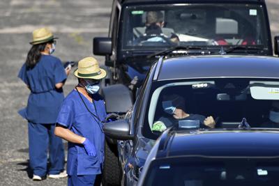 Trabajadores sanitarios realizan pruebas de detección del COVID-19 a pacientes en autos, en Sydney, el 31 de diciembre de 2021. (Bianca De Marchi/AAP Image via AP)