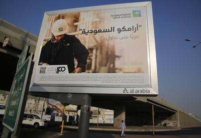 ARCHIVO - Un hombre pasa bajo un cartel con un anuncio de la petrolera estatal saudí Aramco, con el mensaje en árabe "Saudi Aramco, pronto en el mercado de valores", en Yeda, Arabia Saudí, el 12 de noviembre de 2019. (AP Foto/Amr Nabil, Archivo)