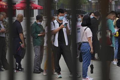Fotografía de archivo del 9 de junio de 2021 de un hombre consultando su celular mientras hace fila con otras personas para recubir una vacuna contra el COVID-19 en Beijing. (AP Foto/Andy Wong, Archivo)