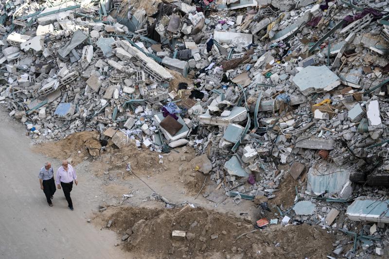 People walk by the rubble of the al-Jalaa building following a cease-fire reached after an 11-day war between Gaza's Hamas rulers and Israel, in Gaza City, Friday, May 21, 2021. The building housed The Associated Press bureau in Gaza City for 15 years. (AP Photo/John Minchillo)