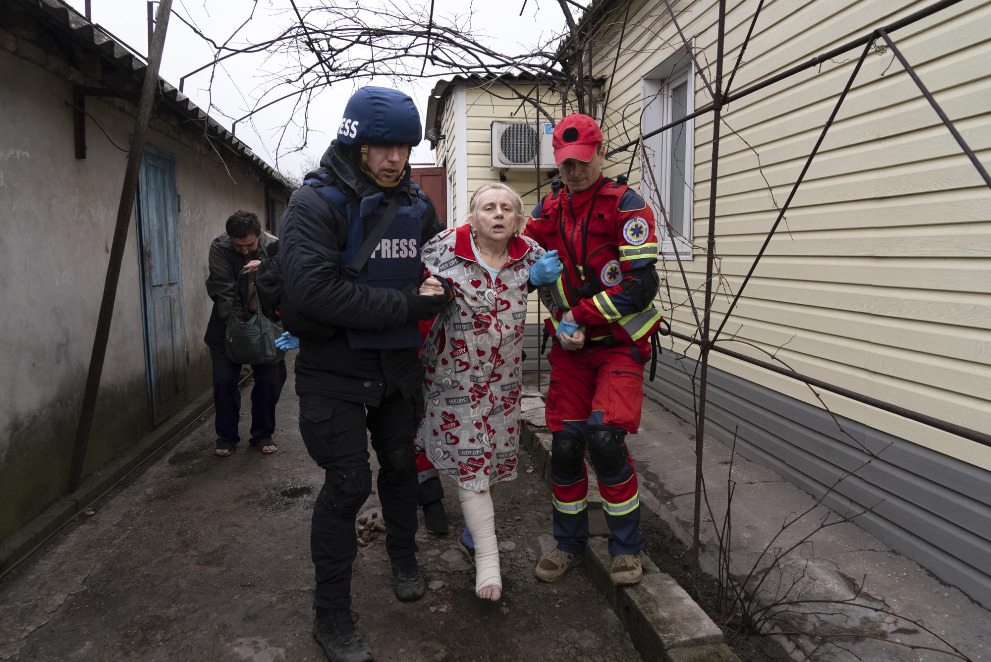 Associated Press photographer Evgeniy Maloletka helps a paramedic to transport a woman injured during shelling in Mariupol, eastern Ukraine, Wednesday, March 2, 2022. (AP Photo/Mstyslav Chernov)