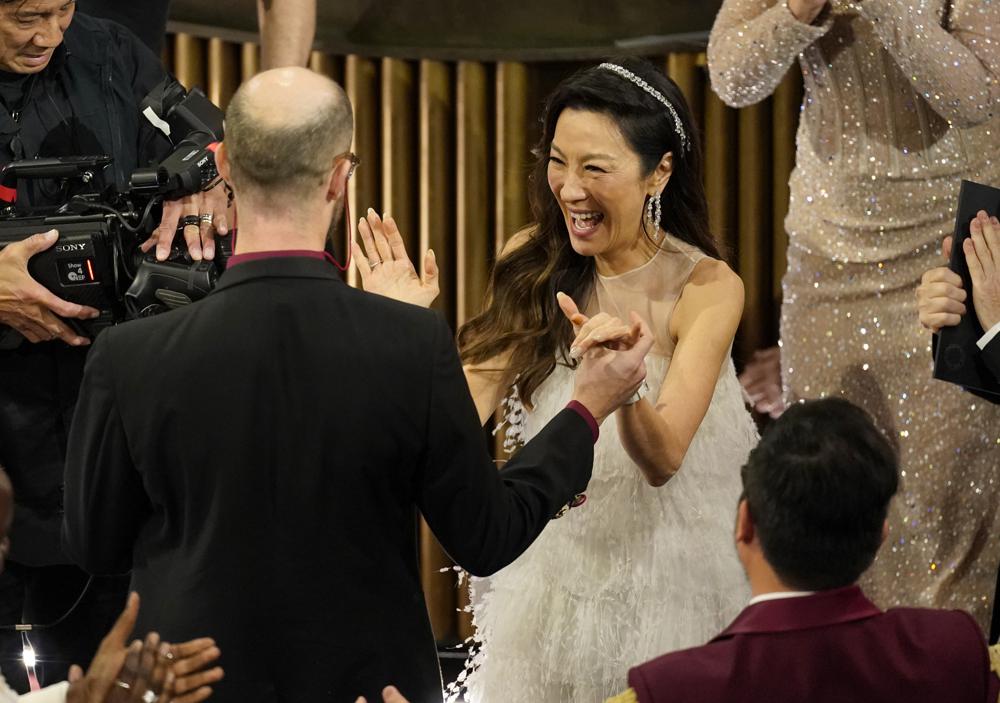 Michelle Yeoh, center, reacts with excitement as Daniel Scheinert, left, and Daniel Kwan accept the award for best director for "Everything Everywhere All at Once" at the Oscars on Sunday, March 12, 2023, at the Dolby Theatre in Los Angeles. (AP Photo/Chris Pizzello)