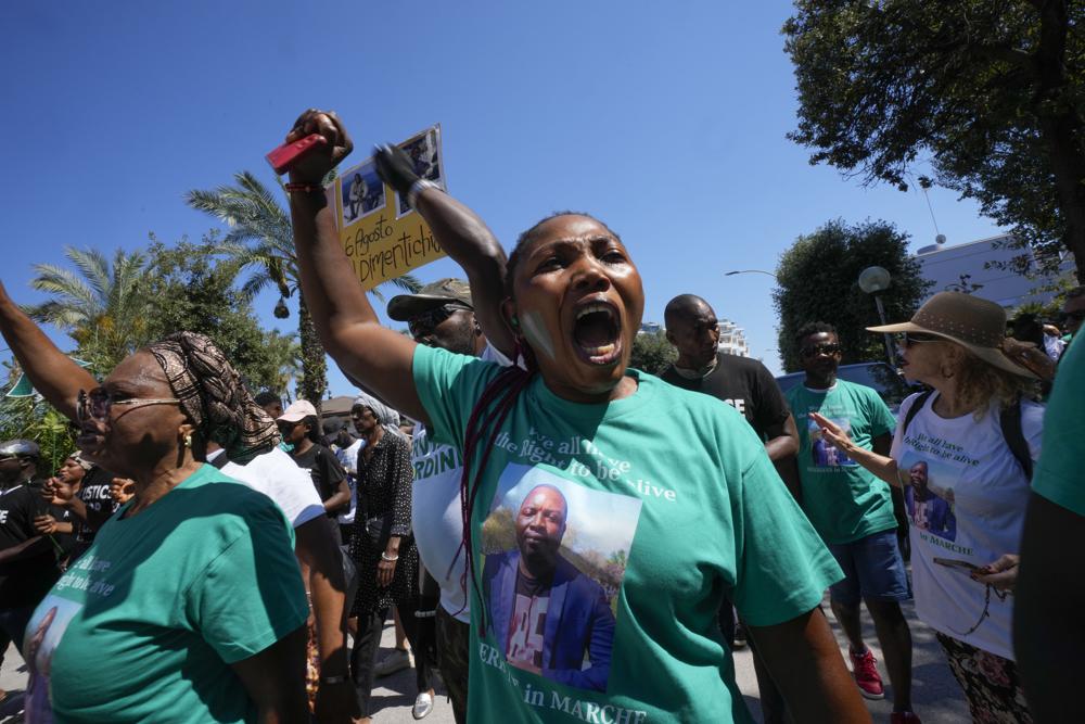 A woman wears a t-shirt with the picture of Nigerian street vendor Alika Ogorchukwu and a writing reading: We all have the right to be alive, during a protest in Civitanova Marche, Italy, Saturday, Aug. 6, 2022. The brutal killing of Ogorchukwu in broad daylight has sparked a debate in this well-to-do Adriatic beach community over whether the attack by an Italian man with a court-documented history of mental illness was racially motivated. (AP Photo/Antonio Calanni)