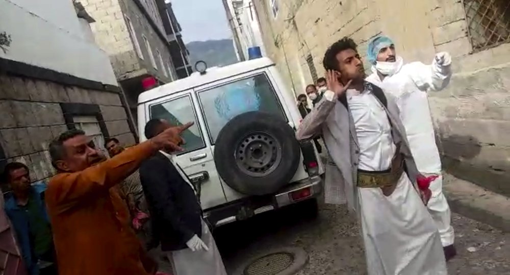 This May 2020 frame grab from video provided by a Yemeni Community activist, shows an activist wearing protective gear and others arguing with a person in the neighborhood, while collecting the lifeless body of a COVID-19 victim, after medics declined to take the body, in the Houthi-controlled city of Ibb, Yemen. (Courtesy of a Yemeni Community Activist via AP)