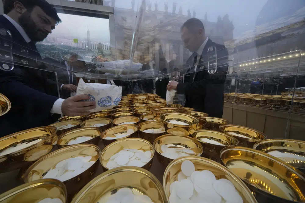 Una persona llena cuencos con la sagrada comunión antes del funeral del papa emérito Benedicto XVI en la Plaza de San Pedro, en el Vaticano, el 5 de enero de 2023. (AP Foto/Andrew Medichini)