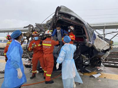 Fotografía difundida por la agencia noticiosa china Xinhua de rescatistas ayudando a un pasajero salir de un tren dañado después de que se descarriló en el condado de Rongjiang, en la provincia de Guizhou, el sábado 4 de junio de 2022. (Xinhua vía AP)