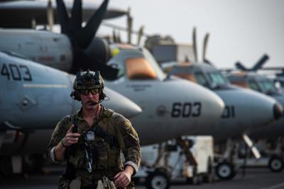 En esta fotografía facilitada por la Armada de Estados Unidos, el técnico de eliminación de artefactos explosivos de tercera clase Ethan Tews cruza la cubierta de vuelo del portaaviones Ronald Reagan para abordar un helicóptero MH-60S SeaHawk y partir rumbo a un petrolero que fue atacado frente a las costas de Omán, en el Mar Arábigo, el viernes 30 de julio de 2021. (Especialista en comunicación masiva de 2da clase Quinton A. Lee/Armada de Estados Unidos vía AP)