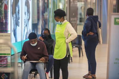 Varias personas esperan para vacunarse contra el COVID-19 en un centro comercial en Johannesburgo, Sudáfrica, el viernes 26 de noviembre de 2021. (AP Foto/Denis Farrell)