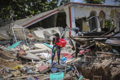 Unas mujeres recuperan sus pertenencias de sus casas destrozadas el domingo 15 de agosto de 2021, en Los Cayos, Haití, luego de un terremoto de magnitud 7,2. (AP Foto/Joseph Odelyn)