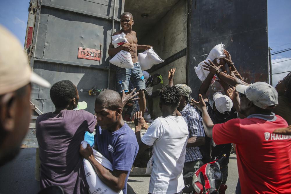 Varias personas se acercan para recibir arroz en Les Cayes, Haití, el lunes 16 de agosto de 2021, dos días después de que un terremoto de magnitud 7,2 sacudiera la parte suroeste de la nación más pobre del hemisferio occidental. (Foto AP/Joseph Odelyn)