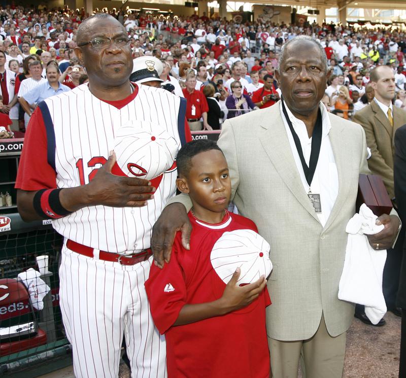 FILE - In this June 20, 2009, file photo, Cincinnati Reds manager Dusty Baker, left, stands with his son Darren Baker, center, and baseball great Hank Aaron as the national anthem is played at the Civil Rights Game ceremony before a game between the Chicago White Sox and the Cincinnati Reds in Cincinnati. Baker, now the manager of the Houston Astros, and Brian Snitker, manager of the Atlanta Braves, say Aaron would have loved being able to watch this World Series. (AP Photo/David Kohl, File)