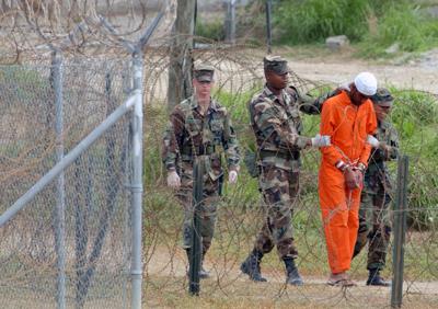 ARCHIVO - En esta foto de archivo del 6 de febrero de 2002, un detenido es llevado por la policía militar a interrogatorio en el Campamento Rayos X de la Base Naval de EEUU en la Bahía de Guantánamo, Cuba. (AP Foto/Lynne Sladky, Archivo)