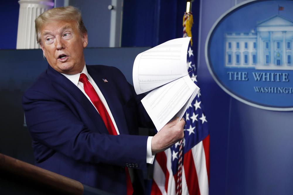 FILE - President Donald Trump holds up papers as he speaks about the coronavirus in the James Brady Press Briefing Room of the White House, April 20, 2020, in Washington. As president, Donald Trump never liked to leave a paper trail. He avoided email, admonished aides to stop taking notes during meetings and ripped up documents when he finished with them.  But Trump was unwilling to part with some of his administration's records when he left the White House last year, whisking them away to Mar-a-Lago, his Florida resort. (AP Photo/Alex Brandon, File)