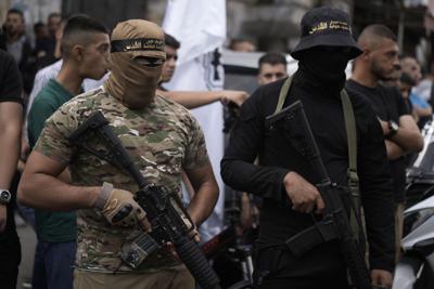 Hombres armados portan cintas del Yihad Islámico en la cabeza durante un funeral en el campamento de refugiados de Yenín, Cisjordania, el viernes 14 de octubre de 2022. (AP Foto/ Majdi Mohammed)