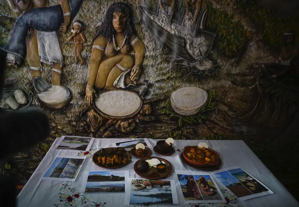 Un mural muestra la preparación del casabe junto con otros platos preparados con yuca, en el restaurante Yucasabi, en La Habana, Cuba, el sábado 13 de mayo de 2023. El casabe está entre los primeros alimentos que los españoles adoptaron e incorporaron a su dieta a su llegada, en parte por su durabilidad. Puede durar meses en buen estado una vez horneado. (AP Foto/Ramón Espinosa)