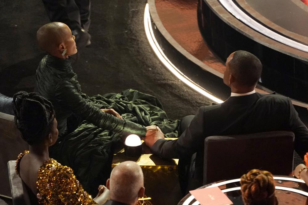 Jada Pinkett Smith, a la izquierda, y Will Smith se toman de la mano en la audiencia de los Oscar el domingo 27 de marzo de 2022 en el Dolby Theatre de Los Ángeles.  (Foto AP/Chris Pizzello)