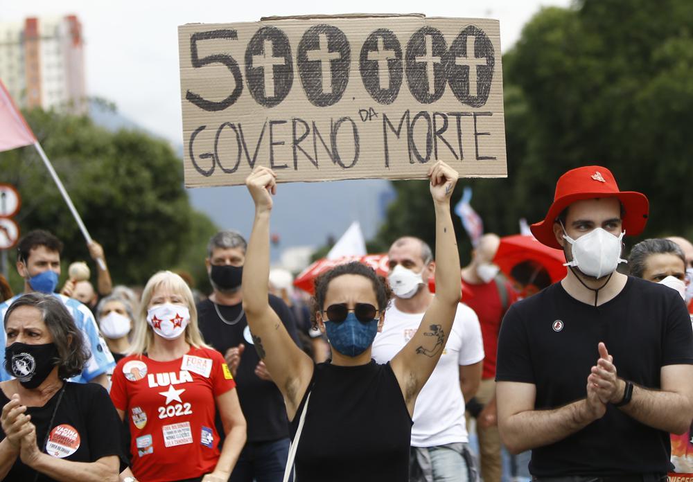 Eine Frau, die eine schützende Gesichtsmaske trägt, hält ein Schild mit einer Nachricht auf Portugiesisch; "500.000, Regierung des Todes" während eines Protests gegen den Umgang des brasilianischen Präsidenten Jair Bolsonaro mit der Coronavirus-Pandemie und die Wirtschaftspolitik, von der sie sagen, dass sie den Interessen der Armen und der Arbeiterklasse schadet, in Rio de Janeiro, Brasilien, Samstag, 19. Juni 2021. Brasilien nähert sich einer offiziellen COVID-19-Todesrate von 500.000 – der zweithöchsten der Welt. (AP-Foto/Bruna Prado)