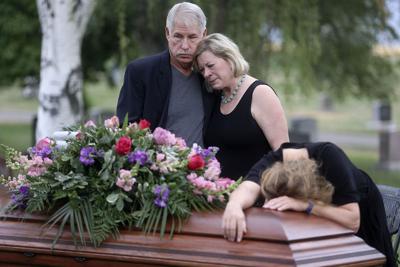 Clark Knighton and Shari Knighton hug as Tricia Wright weeps over the casket of Shari and Tricia's sister, Shawna Wright, who died of heat exhaustion while homeless, during Shawna Wright's interment at Mount Olivet Cemetery in Salt Lake City on Tuesday, July 13, 2021.(Kristin Murphy/The Deseret News via AP)