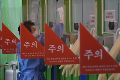 Una trabajadora sanitaria, vestida con un traje de protección, desinfecta una clínica temporal de detección del coronavirus, en Seúl, Corea del Sur, el 25 de enero de 2022. (AP Foto/Lee Jin-man)