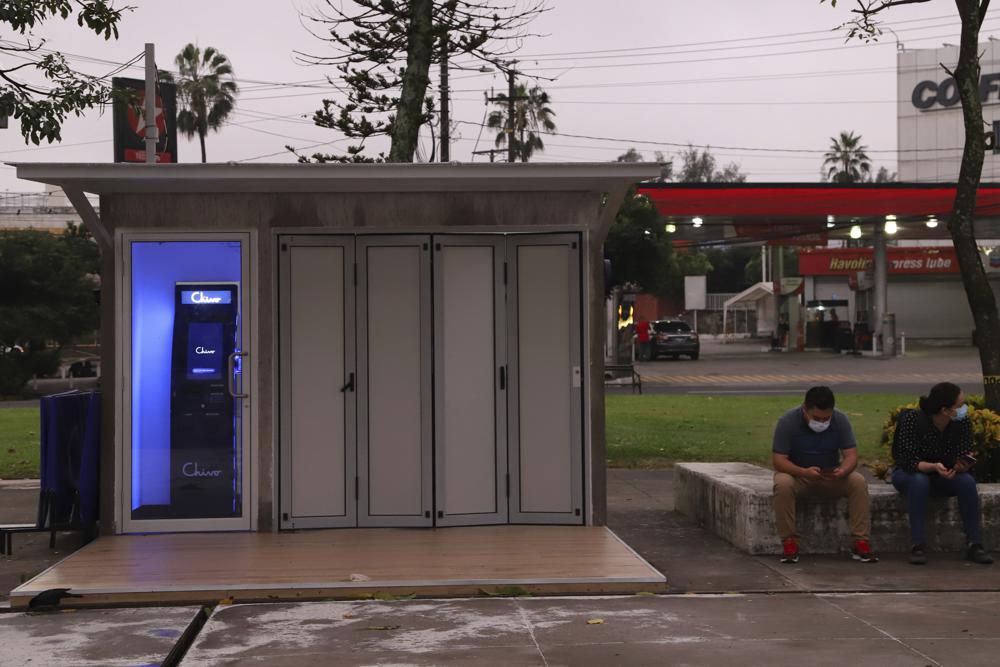 Empleados del gobierno esperan la apertura de la máquina de billetera digital Chivo, que cambiará efectivo por criptomonedas bitcoin en la Plaza Las Américas en San Salvador, El Salvador, el martes 7 de septiembre de 2021. (AP Foto/Salvador Meléndez)
