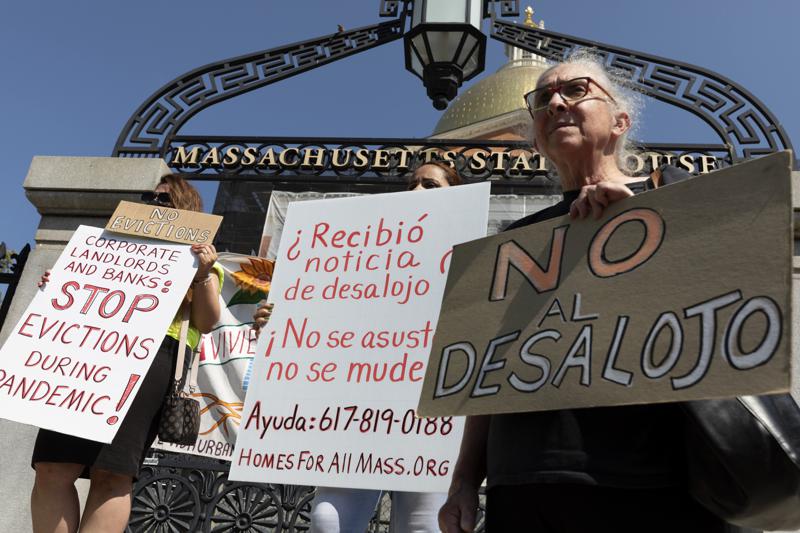 People from a coalition of housing justice groups hold signs protesting evictions during a news conference outside the Statehouse, Friday, July 30, 2021, in Boston. (AP Photo/Michael Dwyer)