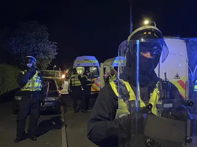 Police officers stand guard on Howell Road in Cardiff as they face a large scale disorder at the scene of a serious road traffic collision on Snowden Road in Ely, Cardiff, Tuesday, May 23, 2023. A few cars were set on fire and objects were hurled at police after a traffic accident Monday night in the Welsh capital Cardiff grew into what officials described as “large-scale disorder.”(Bronwen Weatherby/PA via AP)