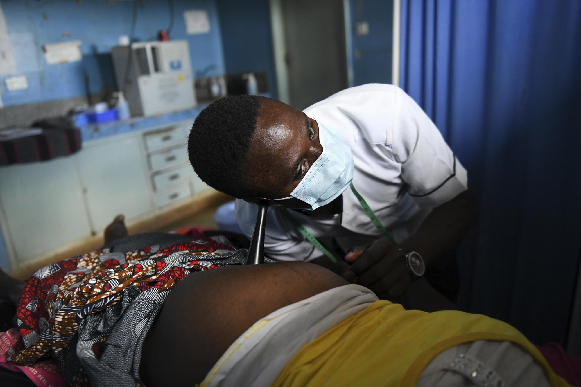 A midwife listens to an unborn baby's heartbeat at Malawi Government's Mauwa Health Centre labour ward, in Chiradzulu, southern Malawi on Wednesday May 26, 2021. Health officials in Malawi say fewer women are getting prenatal care amid the COVID-19 pandemic. At risk are the developing country's gains on its poor rate of maternal deaths. (AP Photo/Thoko Chikondi)