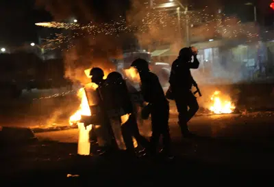 Policías se enfrentan en medio de barricadas incendiadas e a manifestantes que exigen la renuncia de la presidenta Dina Boluarte y los legisladores, así como la realización inmediata de comicios, la libertad del destituido mandatario Pedro Castillo y justicia para los caídos, durante una movilización cerca de la Carretera Panamericana norte en Chao, noroeste de Perú, el viernes 17 de febrero de 2023. (AP Foto/Martin Mejia)