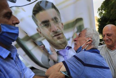 Ibrahim Harb, un libanés de 35 años que sufrió heridas gravísimas en la explosión en el puerto de Líbano murió el 27 de septiembre de 2021, 14 meses después del siniestro. Su padre llora ante el retrato de su hijo durante la procesión fúnebre, martes 28 de setiembre de 2021. (AP Foto/Hussein Malla)