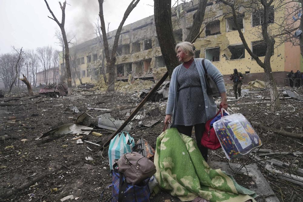 ARQUIVO - Uma mulher caminha do lado de fora de uma maternidade danificada por um bombardeio em Mariupol, Ucrânia, quarta-feira, 9 de março de 2022. (Foto AP/Evgeniy Maloletka, Arquivo)
