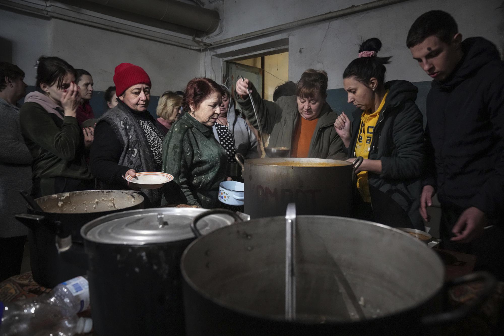 People queue to receive hot food in an improvised bomb shelter in Mariupol, Ukraine, Monday, March 7, 2022. (AP Photo/Evgeniy Maloletka)