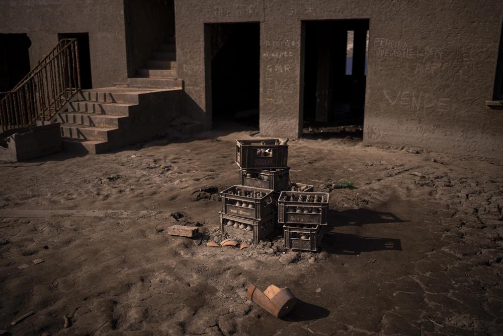 Cajas con botellas viejas de cerveza se ven fotografiadas ante una tienda en el antiguo pueblo de Aceredo, en el noroeste de España, el viernes 11 de febrero de 2022. Los tejados asomando en el agua se han convertido en una escena habitual en verano en el embalse de Lindoso, en el noroeste de España. En años especialmente secos aparecían partes del antiguo pueblo, sumergido hace tres décadas cuando una presa hidroeléctrica inundó el valle. Pero nunca había reaparecido el pueblo entero en pleno invierno. (AP foto/Emilio Morenatti)