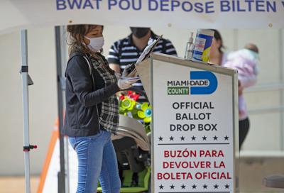 Una trabajadora electoral deposita boletas en un buzón oficial afuera de la Biblioteca Regional Westchester durante la votación anticipada para las elecciones generales en Miami, el 28 de octubre de 2020. (David Santiago/Miami Herald vía AP, Archivo)