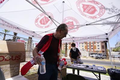 ARCHIVO - Cleon Streitmatter, voluntario del Ejército de Salvación, distribuye botellas de agua en una estación de asistencia debido al calor que alcanzó 45,5 grados centígrados (114 grados Fahrenheit) en Phoenix, el lunes 11 de julio de 2022. (AP Foto/Ross D. Franklin, Archivo)