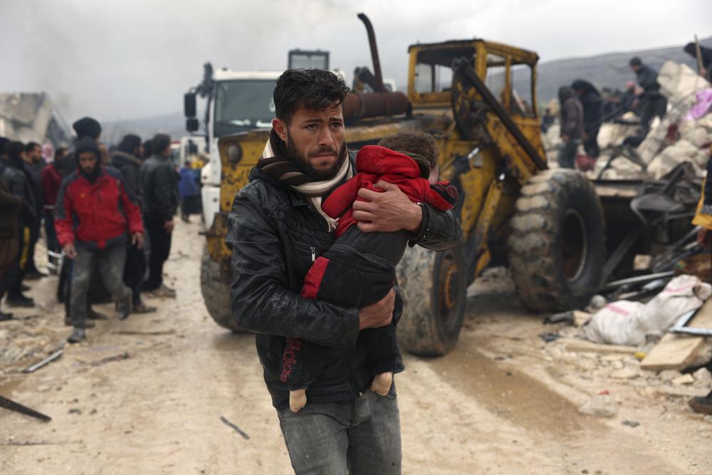 A man carries the body of an earthquake victim in the Besnia village near the Turkish border, Idlib province, Syria, Monday, Feb. 6, 2023. A powerful earthquake has caused significant damage in southeast Turkey and Syria and many casualties are feared. Damage was reported across several Turkish provinces, and rescue teams were being sent from around the country. (AP Photo/Ghaith Alsayed)