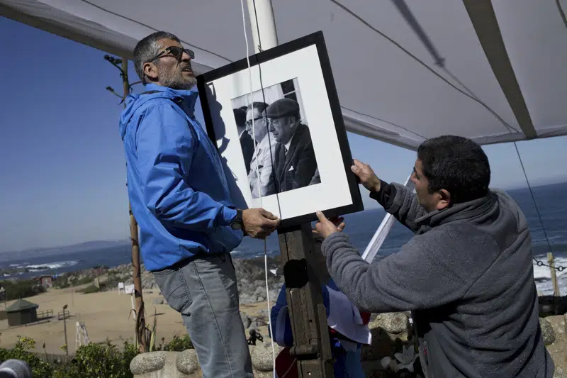 ARCHIVO - Trabajadores colocan un retrato del difunto poeta chileno ganador del Premio Nobel de Literatura Pablo Neruda con el expresidente Salvador Allende en la tumba del bardo después de que lo enterraran nuevamente en Isla Negra, Chile, el 26 de abril de 2016. Expertos forenses tienen previsto informar el 3 de febrero de 2023 sobre las causas de la muerte de Neruda, pero el acto se suspendió.  Un sobrino de Neruda afirmó el lunes 13 de febrero de 2023 que había accedido al informe forense y que este determina que murió envenenado y no por complicaciones del cáncer de próstata.  Neruda tendría 12 días después del golpe militar de 1973 que derrocó a su amigo, el presidente Salvador Allende.  (AP Foto/Esteban Félix, Archivo)