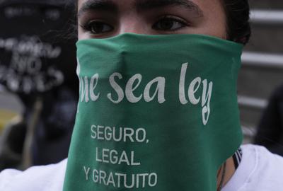 Una mujer usa una mascarilla protectora con un mensaje durante una manifestación por el derecho al aborto, frente a las oficinas de la Conferencia Episcopal de Bolivia, en La Paz, Bolivia, el viernes 29 de octubre de 2021. (AP Foto/Juan Karita)