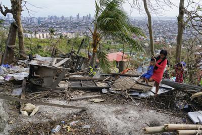 Alona Nacua alza a su hijo para pasar sobre escombros de su casa dañada por el tifón Rai en Cebú, en el centro de Filipinas, el 25 de diciembre de 2021. Nacua dijo que su esposo y ella habían logrado recibir arroz y cuatro pequeñas latas de sardinas y carne en conserva para alimentar a su familia el sábado. "Es la Navidad más triste para mí, ver a mis hijos sufrir de esta manera en este día", añadió Nacua, que está embarazada de su cuarto hijo. (AP Foto/Jay Labra)