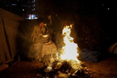 Una persona indigente se protege del frío junto a una figata en Sao Paulo, Brasil, jueves 29 de julio de 2021. Brasil sufre temperaturas históricamente bajas que según el instituto meteorológico persistirán hasta principios de agosto. (AP Foto/Marcelo Chello)
