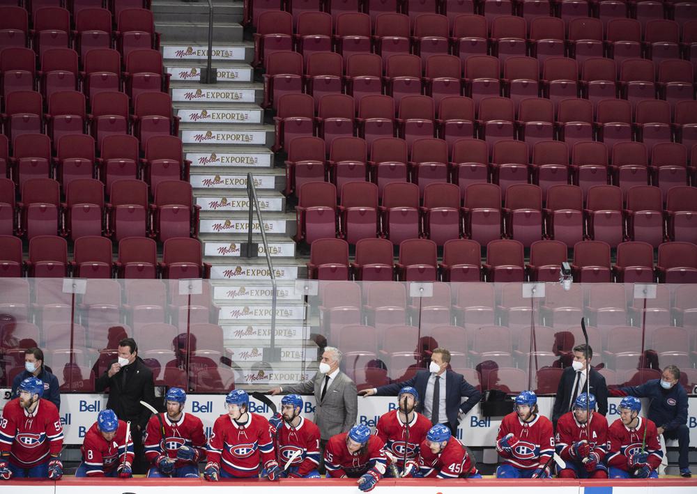 Montreal Canadiens players and coaching staff look on from the bench against a backdrop of empty seats during during second-period NHL hockey game action against the Philadelphia Flyers in Montreal, Thursday, Dec. 16, 2021. (Graham Hughes/The Canadian Press via AP)