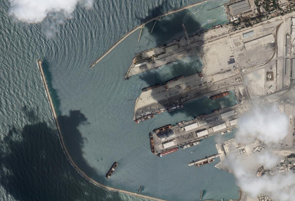 This satellite image from Planet Labs PBC shows the Sierra Leone-flagged cargo ship Razoni, center bottom with four white cranes on its red deck, at port in Tartus, Syria, Monday, Aug. 15, 2022. The first shipment of grain to leave Ukraine under a wartime deal has ended up in Syria, even as that country remains a close ally of Moscow, satellite images analyzed Tuesday by The Associated Press show. (Planet Labs PBC via AP)