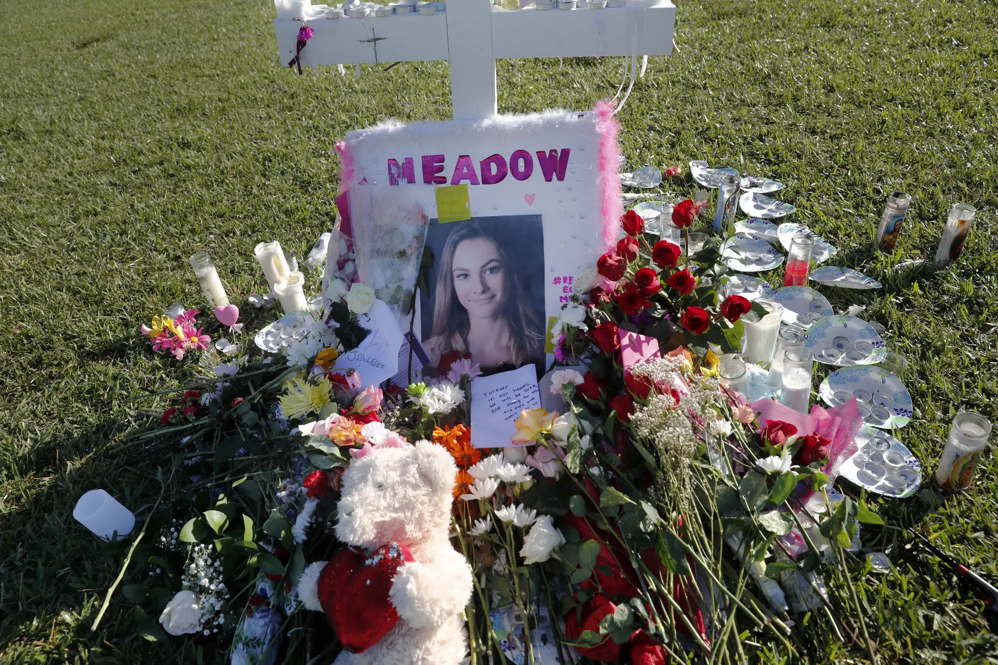 FILE - A photo of Meadow Pollack, one of the seventeen victims who was killed in the Wednesday shooting at Marjory Stoneman Douglas High School, sits against a cross as part of a public memorial, in Parkland, Fla., Saturday, Feb. 17, 2018. (AP Photo/Gerald Herbert, File)