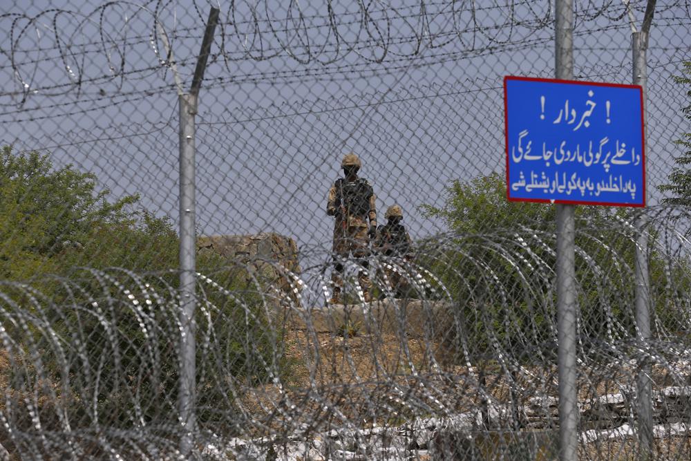 Pakistan Army troops patrol along the fence with a warning board read as 'Beware, Entrance will be shot' on the Pakistan Afghanistan border, in Khyber district, Pakistan, Tuesday, Aug. 3, 2021. Pakistan's military said it completed 90 percent of the fencing along the border with Afghanistan, vowing the remaining one of the most difficult tasks of improving the border management will be completed this summer to prevent any cross-border militant attack from both sides. (AP Photo/Anjum Naveed)