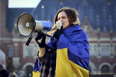 Una mujer está envuelta en la bandera ucraniana y grita a través de un megáfono durante una manifestación frente a la Corte Penal Internacional en La Haya, Países Bajos, el lunes 7 de marzo de 2022. Un representante de Kiev instó al máximo tribunal de las Naciones Unidas a ordenar a Rusia que detenga su devastadora invasión de Ucrania, en una audiencia desairada por Rusia. (AP Foto/Phil Nijhuis)