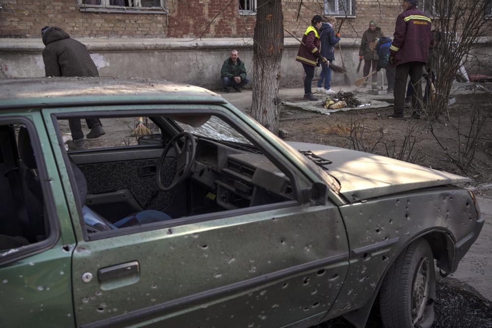 La gente limpia las calles después de que los bombardeos dañaran varios apartamentos en Kiev, Ucrania, el miércoles 23 de marzo de 2022. (Foto AP/Rodrigo Abd)