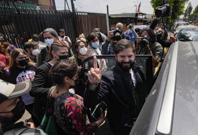 El candidato presidencial chileno Gabriel Boric, del partido Apruebo Dignidad, hace la señal de la V a los fotógrafos después de ver su primer anuncio político televisado de la campaña 2021 en la casa de un simpatizante en La Pintana, barrio de Santiago, Chile, el viernes 22 de octubre.  (AP Foto/Esteban Felix)