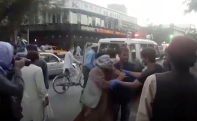 En una imagen tomada de un video, un grupo de personas brindan ayuda a una persona herida cerca del lugar de una explosión mortífera afuera del aeropuerto de Kabul, Afganistán, el jueves 26 de agosto de 2021. (Agencia de Noticias Aśvaka vía AP)