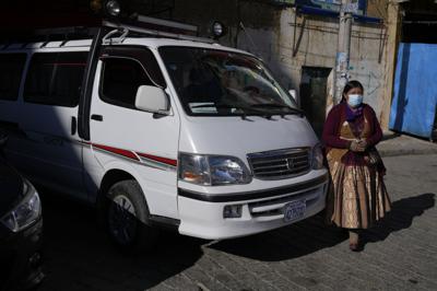 Mery Yujra camina junto a su minibús en El Alto, Bolivia, miércoles 29 de septiembre de 2021.  (AP Foto/Juan Karita)