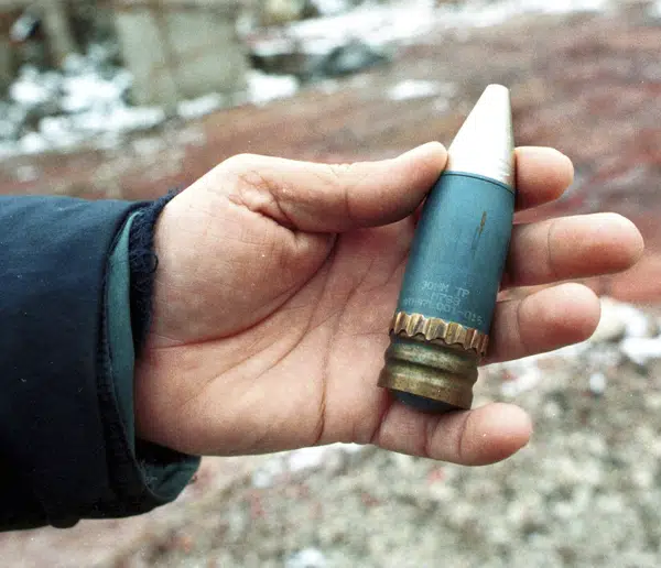 FILE - A member of a radiation team holds a 30mm armor-piercing shell containing depleted uranium, used by NATO during air strikes on Bosnia in 1995, which was found in a former military factory in the suburb of Vogosca, near Sarajevo, Jan. 15, 2001. (AP Photo/Hidajet Delic, File)